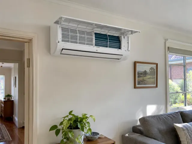 Clean split system with open front panel and visible filters on a living room wall in Prospect